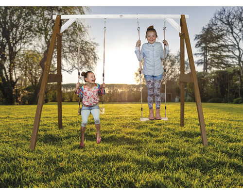 Holzschaukel mit zwei spielenden Mädchen im Garten