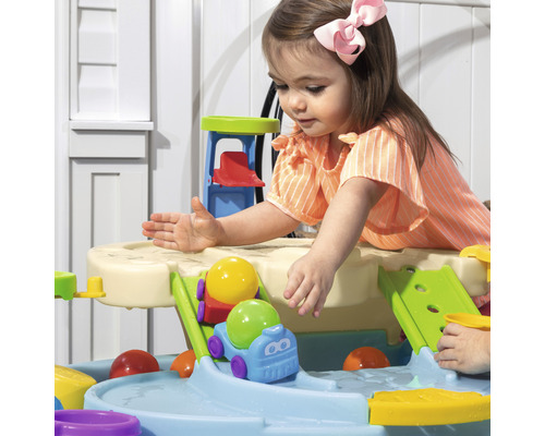 Kind spielt mit einer Wasserbahn im Garten
