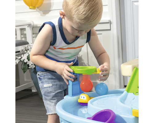 Junge spielt mit einem Wasserspieltisch im Freien.