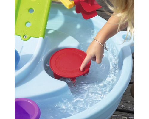 Kind spielt mit einem Wasserspieltisch im Freien