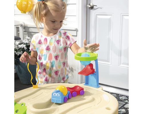 Ein Mädchen spielt mit einem Sand- und Wassertisch mit Zubehör