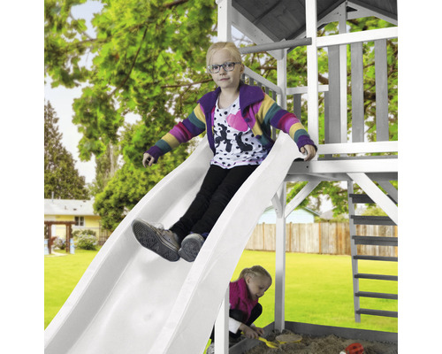 Kind rutscht auf einer Spielplatzrutsche im Garten.