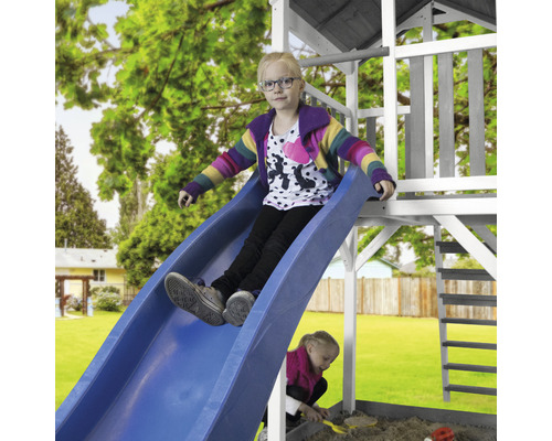 Mädchen rutscht auf einer blauen Rutsche eines Spielturms im Garten