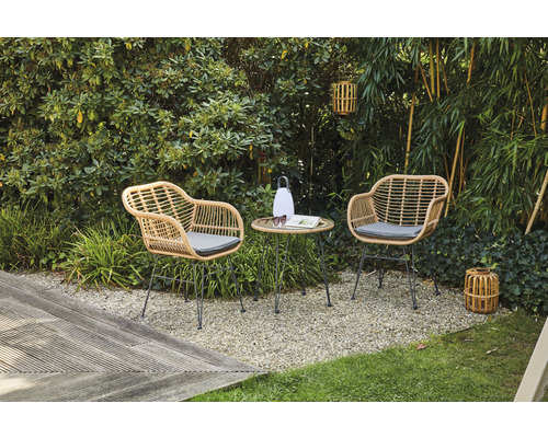 Gartenszene mit zwei Korbsesseln und kleinem Tisch auf Kiesboden