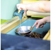 Kind füllt Wasser aus einem Wasserhahn in eine Metallpfanne an einem Spieltisch