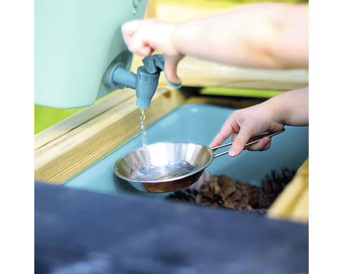 Kind füllt Wasser aus einem Wasserhahn in eine Metallpfanne an einem Spieltisch