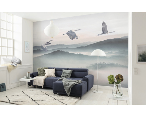 Wohnzimmer mit Fototapete Berglandschaft und Kranichen, Sofa, Teppich und Dekoration.