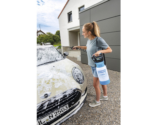 Eine Frau reinigt ein Auto mit einem Akku-Schaumsprüher von Gloria.