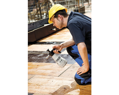 Mann mit Schutzhelm verwendet Drucksprüher auf Baustelle