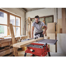 Mann schneidet Holz mit einer Tischkreissäge in einer Werkstatt