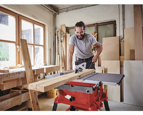 Mann schneidet Holz mit einer Tischkreissäge in einer Werkstatt