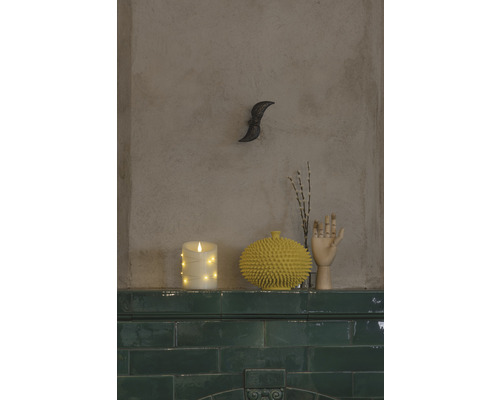 Dekorative Szene mit LED Kerze, stacheliger Vase und Holzhand auf einem grünen Fliesensims.