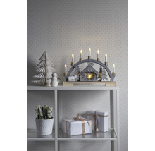 Weihnachtsdekoration mit Lichterbogen, Papierbaum, Schneemann und Geschenken auf einem Regal