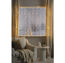 Gemütliches Wohnzimmer mit Lichterketten, Vorhängen, Sessel und Beistelltisch für eine warme Atmosphäre.