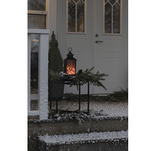 Dekorative Laterne mit Flammeneffekt auf einem Tisch vor einer Haustür im Winter.