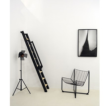 Zimmer mit schwarzer Leiter, Lampe, Stuhl und gerahmtem Bild