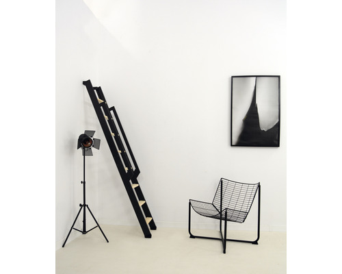 Zimmer mit schwarzer Leiter, Lampe, Stuhl und gerahmtem Bild