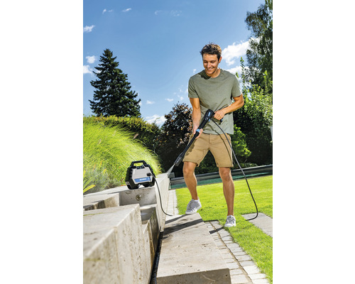 Mann reinigt Steintreppe mit Hochdruckreiniger im Garten.