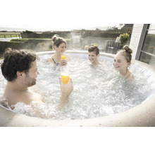 Familie mit Getränken entspannt in einem aufblasbaren Whirlpool im Freien.