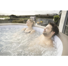 Ein Paar entspannt in einem aufblasbaren Whirlpool im Freien.