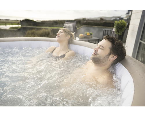 Ein Paar entspannt in einem aufblasbaren Whirlpool im Freien.