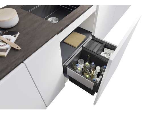 Küchenspüle mit offenem Auszug voller Flaschen und Behälter zur Mülltrennung.