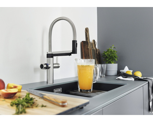 Küchenszene mit Spültischarmatur, Spülbecken, Schneidebrett, Zutaten und Getränkekrug