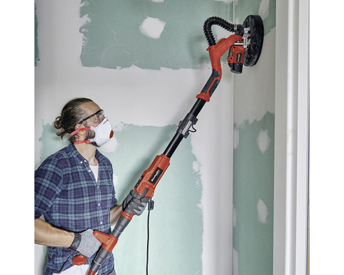 Mann schleift Wand mit einem Langhalsschleifer