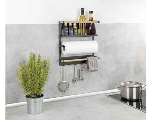 Wandregal mit Küchenutensilien, Gewürzen, Papierrolle und Topf in einer Küche