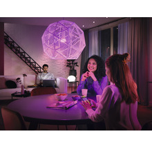 Wohnzimmer mit geometrischer Hängelampe, Tisch und sitzenden Personen