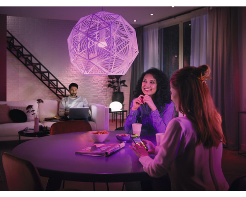 Wohnzimmer mit dekorativer Pendelleuchte, Esstisch und entspannten Personen