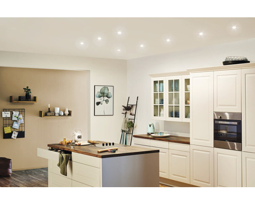 Helle Küche mit Kochinsel, Einbauschränken und Deckenleuchten.