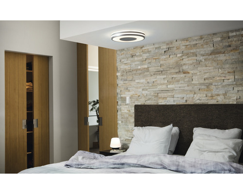 Schlafzimmer mit Doppelbett, Holzschiebetüren, Steinwand und Deckenleuchte
