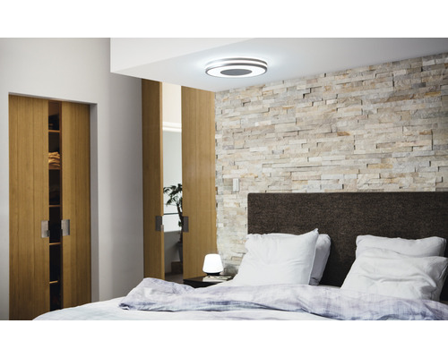 Schlafzimmer mit Deckenleuchte, Steinwand, Bett und Schiebetüren