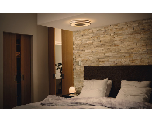 Schlafzimmer mit Doppelbett, Steinwand und runder Deckenleuchte