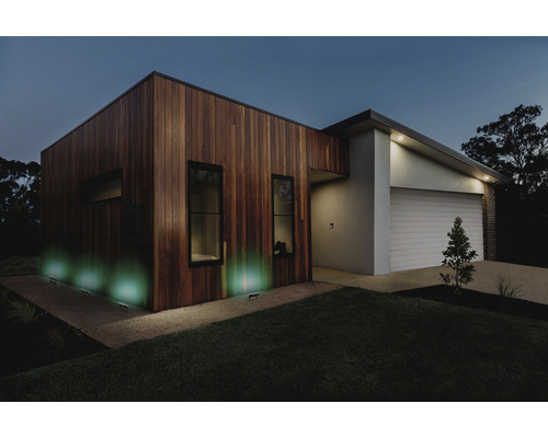Modernes Haus mit Holzfassade und Außenbeleuchtung bei Nacht.