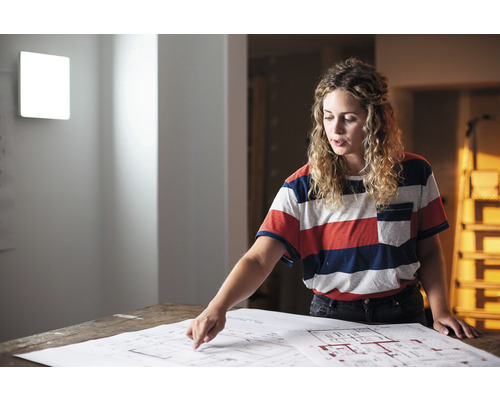 Frau betrachtet Bauplan für Hausrenovierung