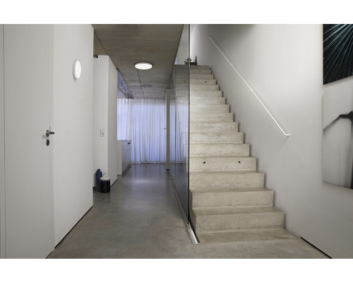 Modernes Interieur mit Betontreppe, Glaswand und indirekter Beleuchtung