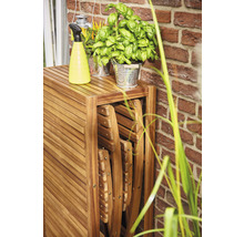 Holztisch mit Klappstühlen, Sprühflasche und Kräutertöpfen im Freien.