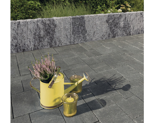 Gartenszene mit Pflastersteinen, Mauer, Gießkanne und Kerzen