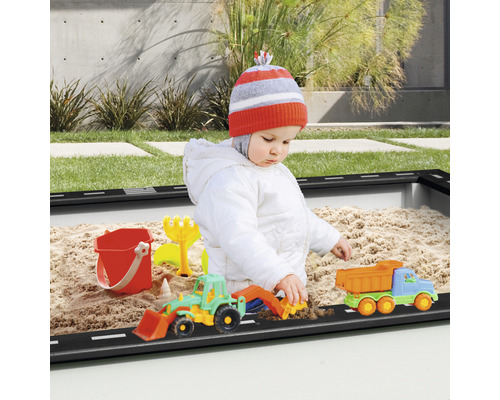 Kleinkind spielt mit Sandkastenspielzeug im Sandkasten