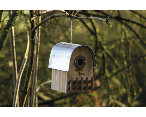 Holzvogelhaus mit Metalldach hängt an einem Baum