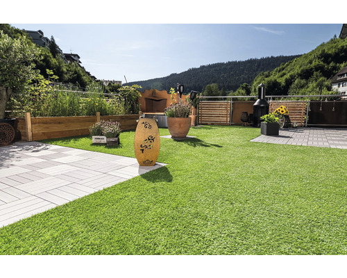 Gestalteter Garten mit Kunstrasen, Pflastersteinen und Bepflanzung