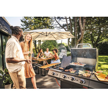 Personen grillen im Garten mit einem Gasgrill unter einem Sonnenschirm und einer Lichterkette.