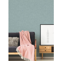 Wohnzimmer mit gemusterter Tapete, Sofa, Kissen, Decke und einem kleinen Schrank mit einem London-Bild