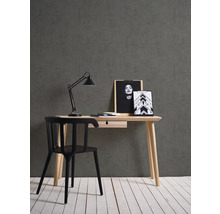 Schreibtisch mit Schublade, Schreibtischlampe und schwarzem Stuhl vor grauer Wand