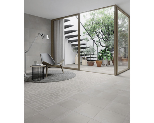 Heller Raum mit Fliesenboden, Sessel, Stehlampe und Blick auf eine Außentreppe mit Pflanzen