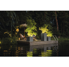 Szene mit Pflanzgefäßen auf einem Holzsteg am Wasser, beleuchtet mit Lichtern