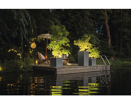 Szene mit Pflanzgefäßen auf einem Holzsteg am Wasser, beleuchtet mit Lichtern