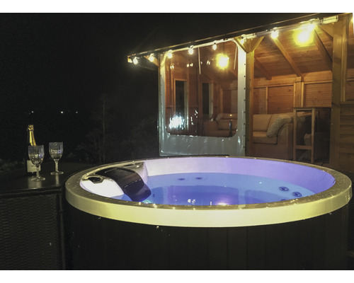 Beleuchteter Whirlpool im Gartenpavillon mit Champagnergläsern